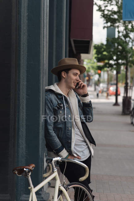 Young man leaning against wall, using smartphone — Stock Photo