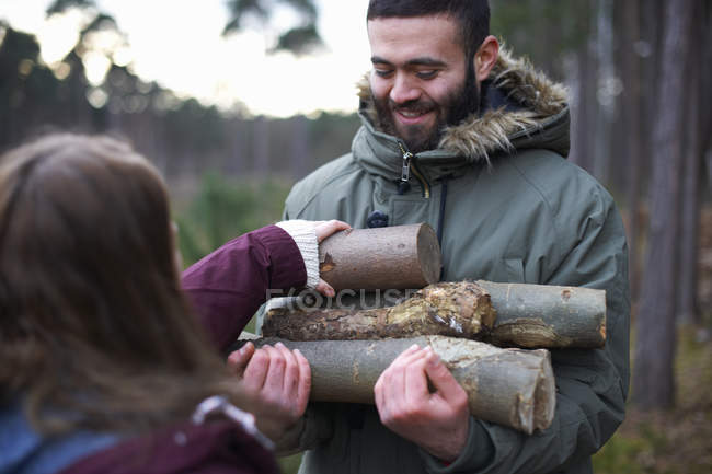 Young hiking couple collecting logs for campfire in forest — Stock Photo