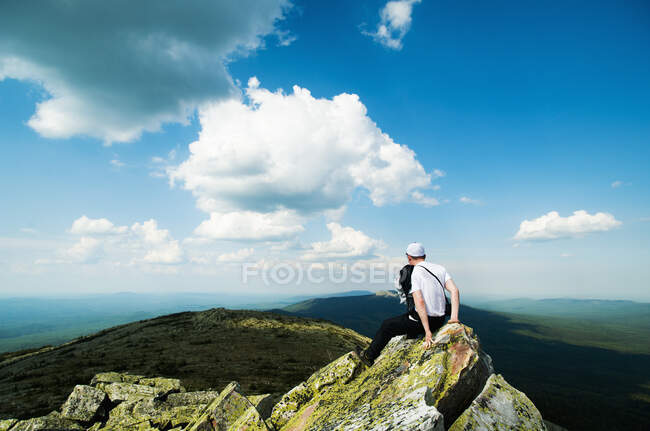 Junger männlicher Wanderer sitzt auf einem Felsen und blickt über die Landschaft, Russland — Stockfoto