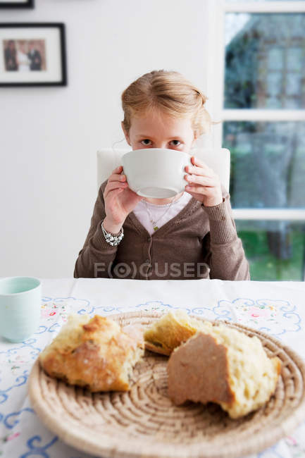 Menina bebendo sopa de tigela na mesa — Fotografia de Stock