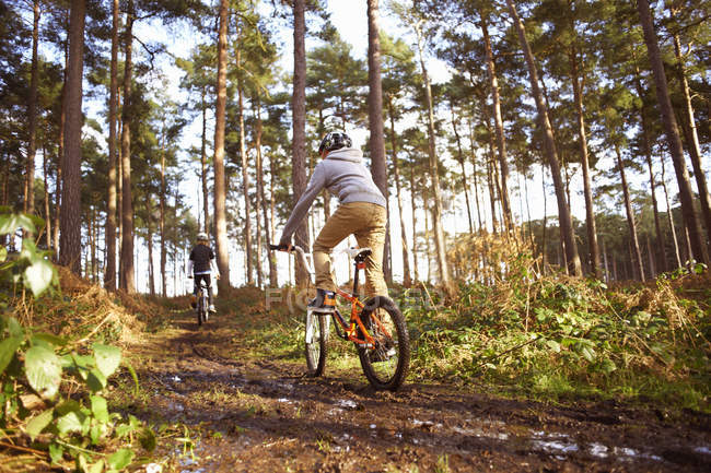 Twin brothers racing BMX bikes in muddy forest — Stock Photo