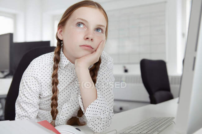 Девушка с рукой на подбородке смотрит вверх в офисе — стоковое фото