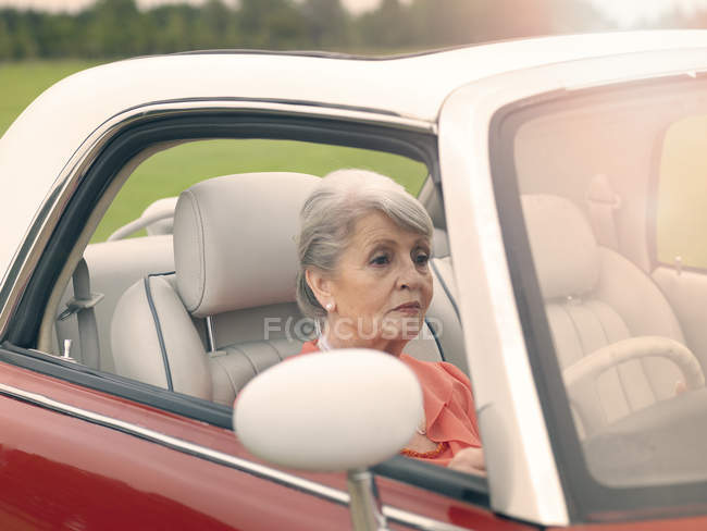 Старша жінка за кермом червоний кабріолет — стокове фото