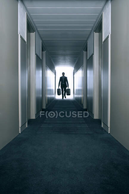 Homme portant des valises dans un couloir — Photo de stock