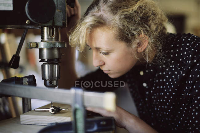 Junge Handwerkerin bohrt Bauteil in Pfeifenorgelwerkstatt — Stockfoto