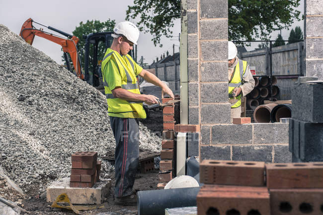 Рабочие кладут кирпичи на строительную площадку — стоковое фото