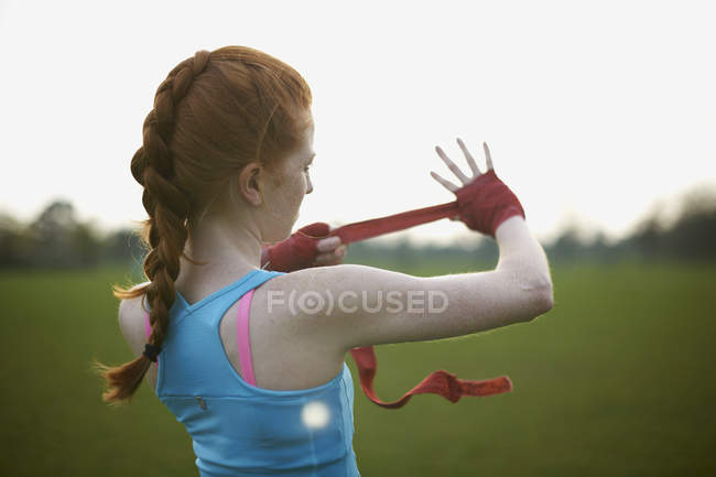 Retrato de una mujer que se pone unos guantes de boxeo en el parque - foto de stock