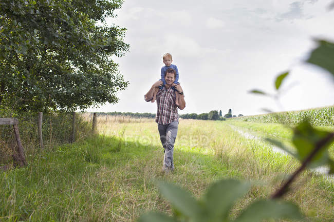 Padre llevando a su hijo en hombros - foto de stock