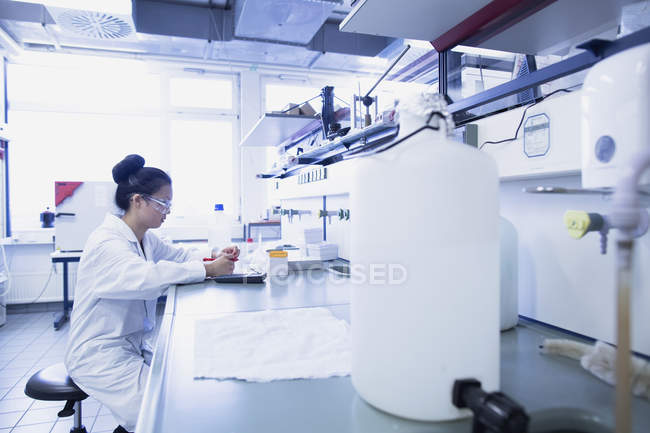 Young female scientist contemplating research notes on lab workbench — Stock Photo