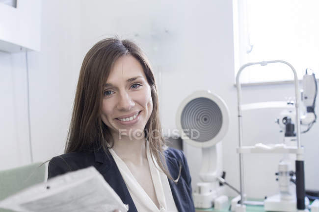 Жінка в офісі оптики дивиться на камеру посміхається — стокове фото