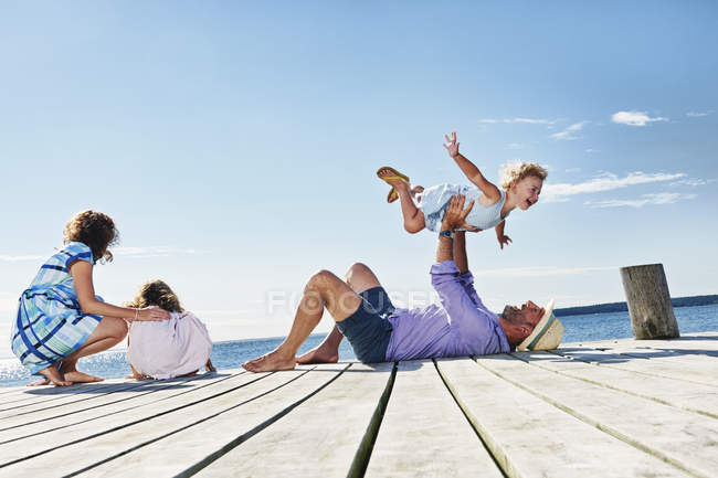 Família brincando no cais de madeira — Fotografia de Stock