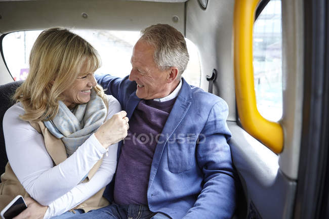 Mature dating couple en route in black cab backseat — Stock Photo
