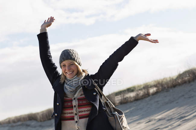 Mujer sonriente de pie en la playa - foto de stock