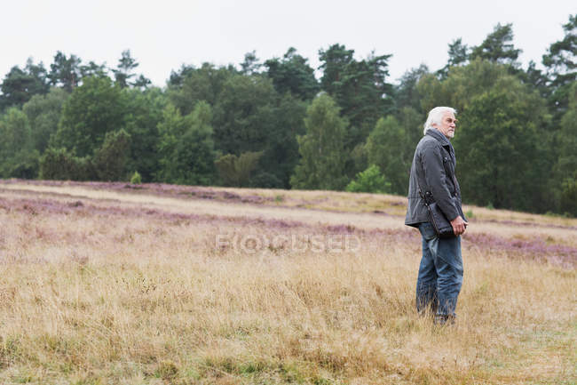 Uomo anziano in piedi nel prato — Foto stock