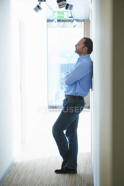 Hombre maduro apoyado contra la pared en el pasillo - foto de stock