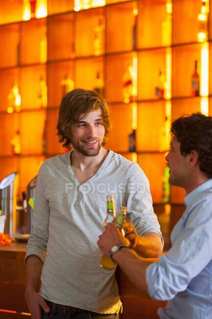 Два чоловіки стоять у барі з пляшками пива — стокове фото