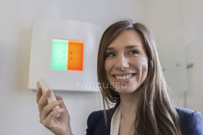 Woman in opticians office holding remote control looking away smiling — Stock Photo