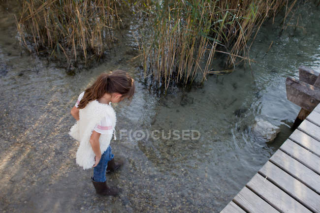 Chica en botas caminando en el estanque - foto de stock