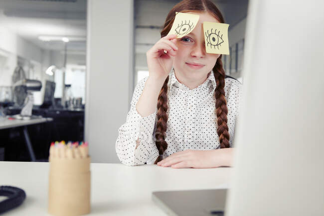 Menina no escritório com notas adesivas cobrindo os olhos, espreitando — Fotografia de Stock