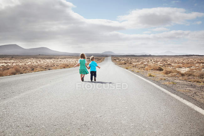 Kinder laufen auf gepflasterter Landstraße — Stockfoto