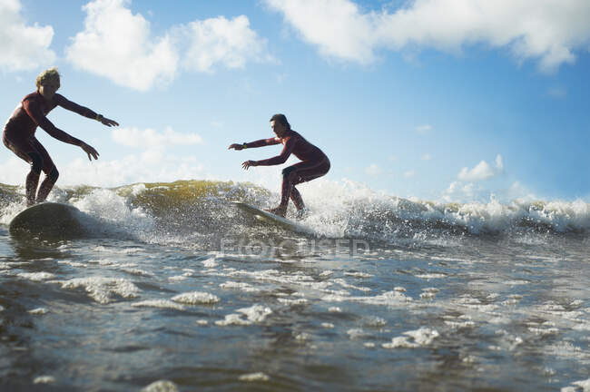 Two surfers riding wave — Stock Photo