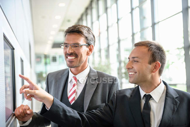 Businessmen pointing and looking at wall screen — Stock Photo