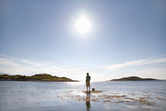 Mann steht auf Felsen im Meer — Stockfoto