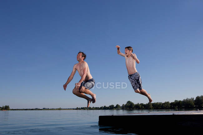 Padre e figlio che saltano nel lago — Foto stock