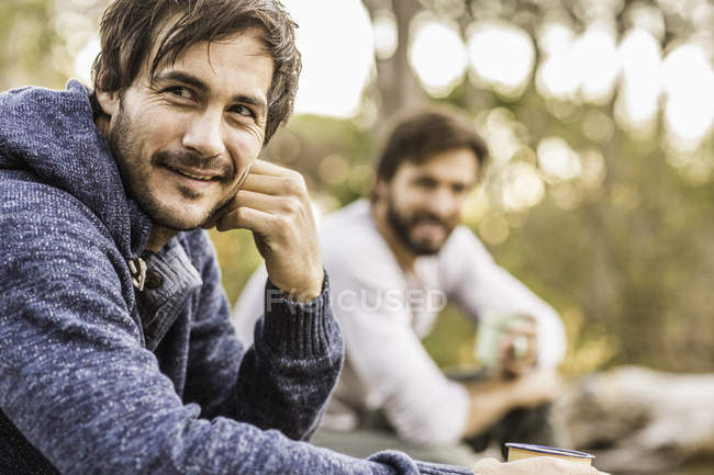 Dos hombres sentados en el bosque bebiendo café, Deer Park, Ciudad del Cabo, Sudáfrica - foto de stock