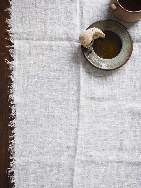 Half eaten bread roll on plate on tablecloth — Stock Photo