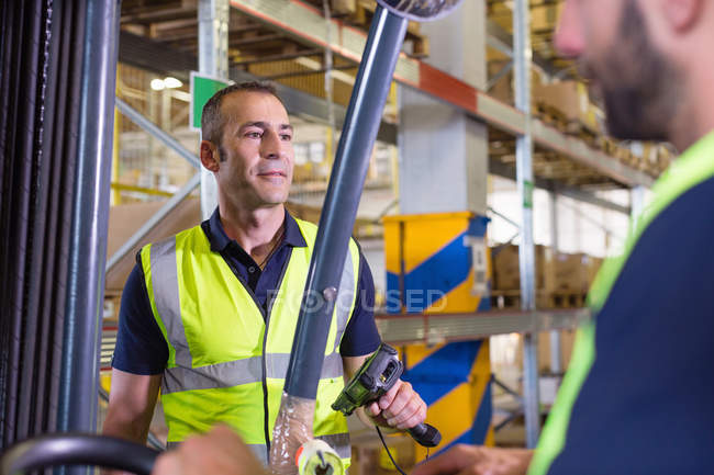 Supervisor instructing male forklift truck driver in distribution warehouse — Stock Photo