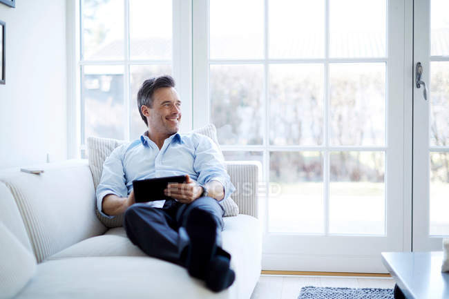 Mann entspannt sich auf Sofa und nutzt digitales Tablet — Stockfoto