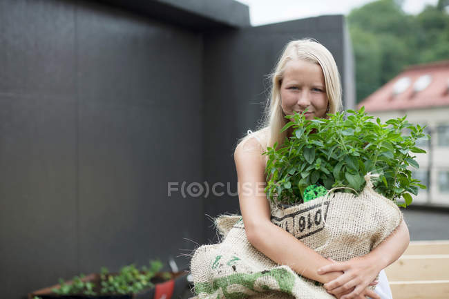 Adolescente menina segurando saco de plantas — Fotografia de Stock