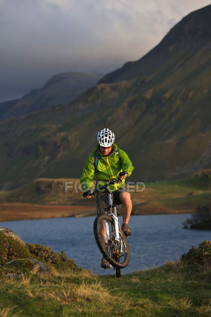 Mountain biker on grassy hillside — Stock Photo