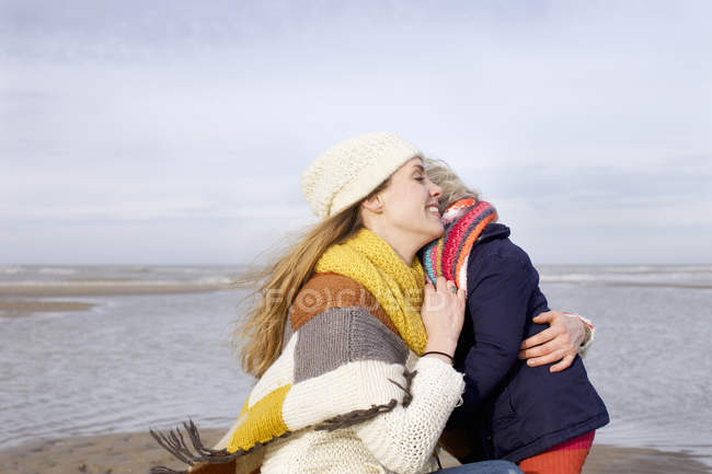 Mulher adulta média abraçando filha na praia, Bloemendaal aan Zee, Holanda — Fotografia de Stock
