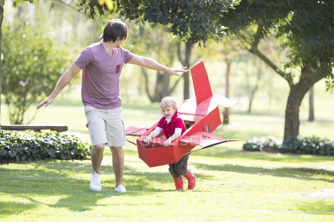Vater und Sohn rennen mit Spielzeugflugzeug in Park — Stockfoto