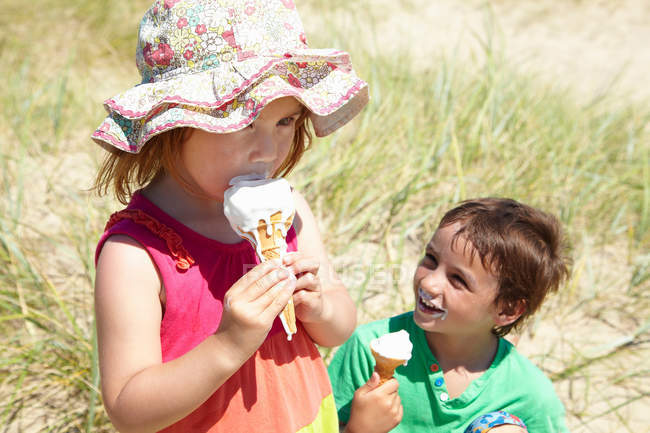 Niños comiendo helado en la playa - foto de stock