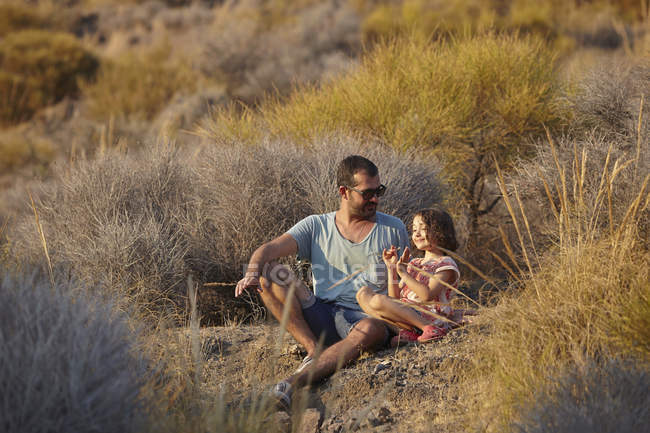 Father and daughter sitting on hillside, Almeria, Andalusia, Spain — Stock Photo