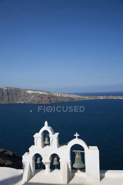 Vista al mar y al campanario blanco de la iglesia lavada, Oia, Santorini, Cícladas, Grecia - foto de stock