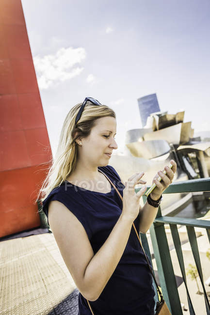 Jovem mulher lendo textos de smartphones, Bilbau, Espanha — Fotografia de Stock