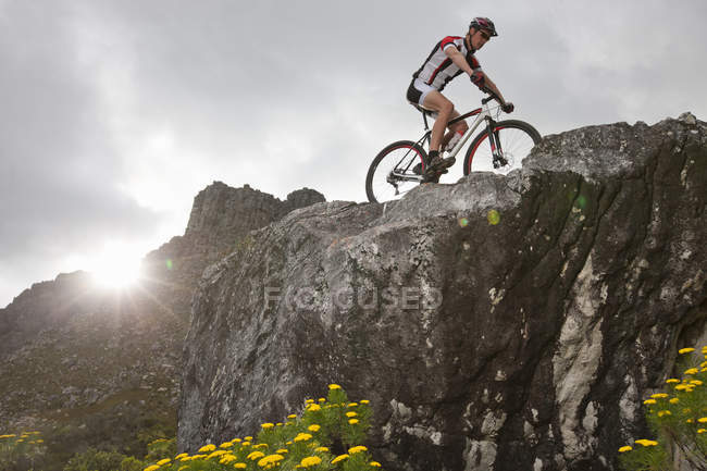 Giovane uomo mountain bike sulla cima della formazione rocciosa — Foto stock