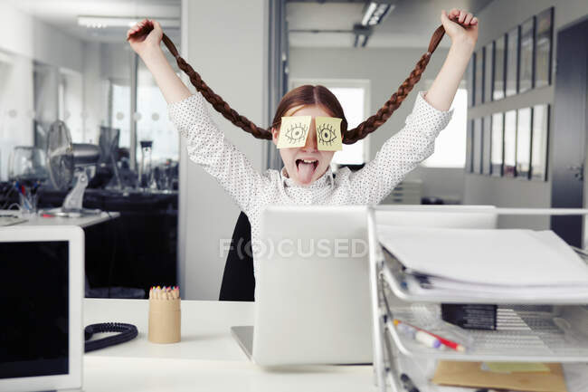Menina no escritório com notas adesivas cobrindo olhos segurando tranças — Fotografia de Stock