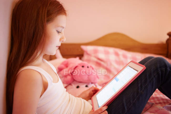 Chica usando tableta digital en el dormitorio - foto de stock