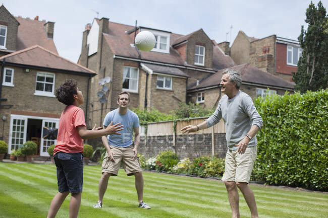 Three generation family playing with football in garden — Stock Photo