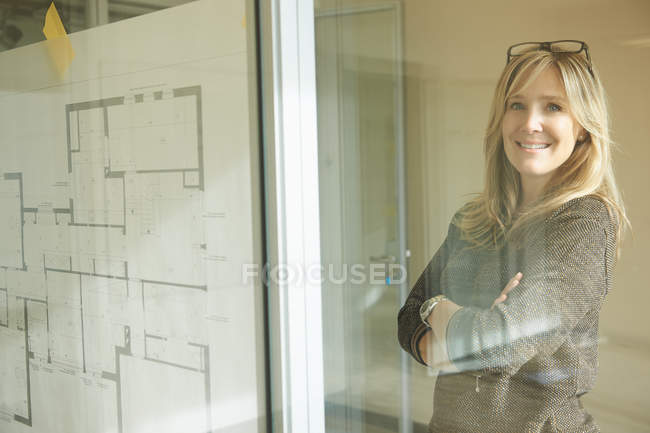 Архитектор смотрит на планы, приклеенные к стеклянной стене — стоковое фото