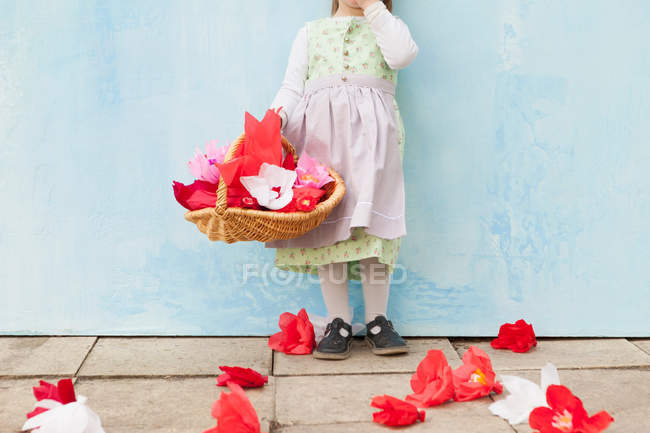 Niña sosteniendo cesta de flores de papel - foto de stock
