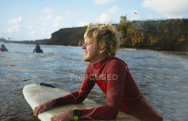 Surfista masculino no mar, segurando prancha, descansando — Fotografia de Stock