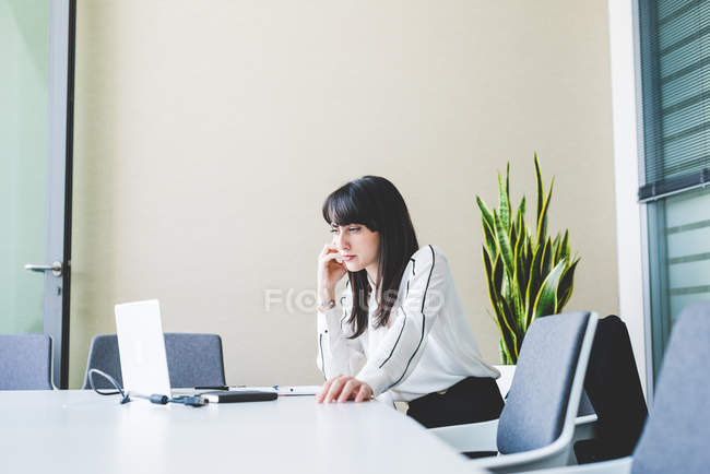 Бізнес-леді дивиться за ноутбуком на офісному столі — стокове фото