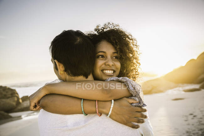 Casal abraçando na praia ao pôr do sol — Fotografia de Stock
