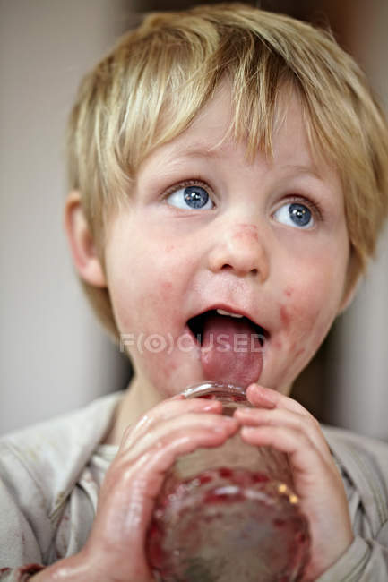 Boy eating jam from jar, focus on foreground — Stock Photo
